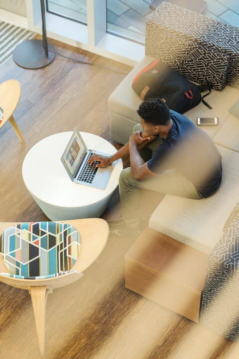 man-using-gray-laptop-while-sitting-on-beige-sofa