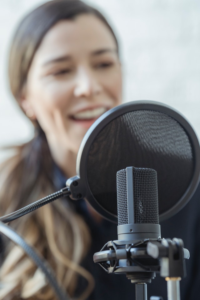 happy-woman-smiling-while-recording-voice-with-microphone